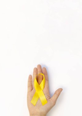 Elinde sarı kurdele olan dikey bir poster. Çocukluk Kanseri Farkındalık Günü afişi için boşluk kopyala