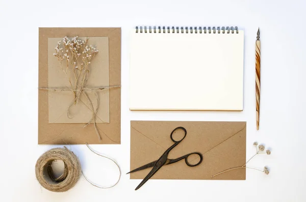 Flat lay Envelope de papel artesanal com caderno em espiral em branco e acessórios para artesanal: cordel e tesoura. Mockup carta vintage com caneta-tinteiro em branco — Fotografia de Stock