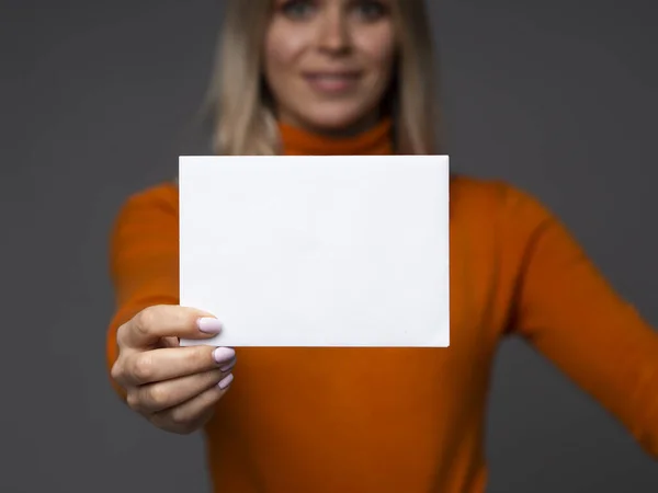Empresária segura maquete de cartão em branco com espaço para texto em um fundo cinza — Fotografia de Stock