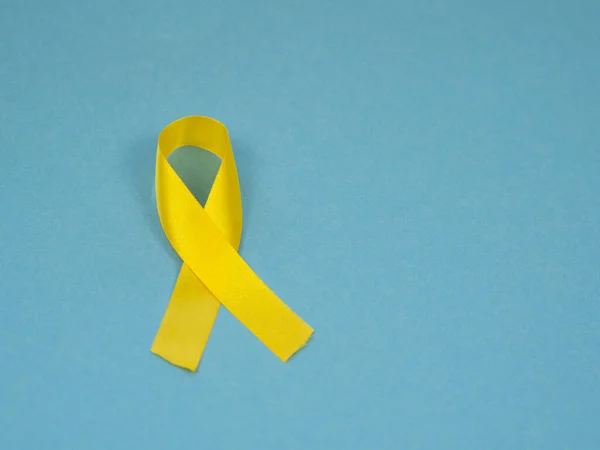 Flat lay February, 15 Childhood Cancer Awareness symbol Gold Ribbon on a blue background — ストック写真