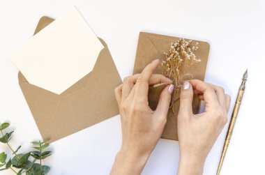 Üst düzey kadın çalışma alanı, el işi kağıt zarf, beyaz arka planda boş kağıt maketi. Romantik mektup, kadın eli hediye paketi.