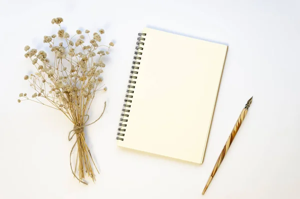 Vista superior de la maqueta de cuaderno en espiral en blanco con pluma estilográfica decorada con un ramo seco en una mesa blanca. Piso con espacio de copia para caligrafía caligrafía carta — Foto de Stock