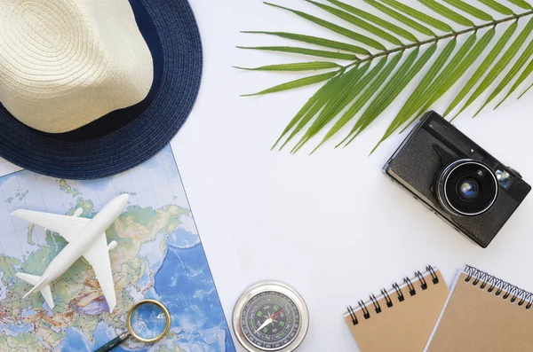 Plat plage et accessoires de voyage : chapeau, branches de palmier et carte avec boussole. Vue du dessus sur fond blanc — Photo