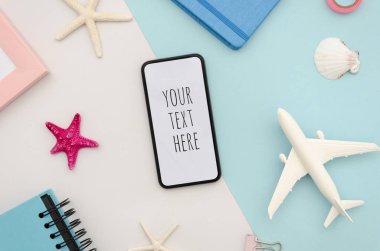 Düz siyah akıllı telefon, büyük boş ekran ve daha az modern çerçeve tasarımlı. Üst görünüm seyahat modeli uçak oyuncakları ve pastel arka planda deniz yıldızları