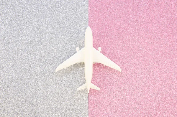 Top vue modèle avion jouet sur un fond de papier paillettes argent et rose. Voyage plat minimum laïc — Photo