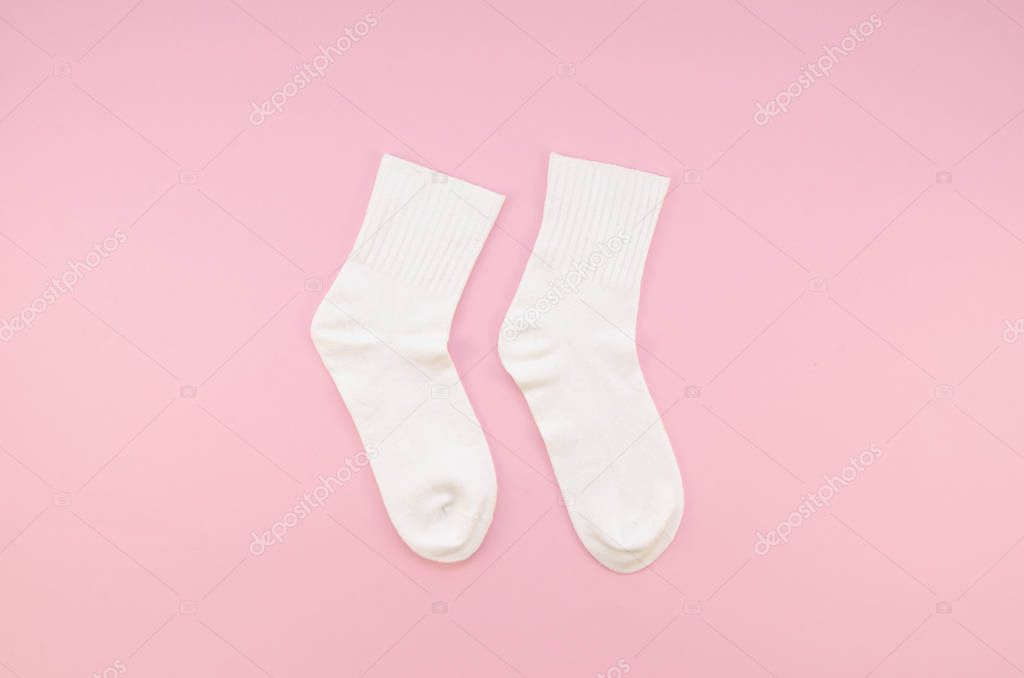 Flat lay Pair of white cotton socks on a pastel pink background. Top view childrens socks