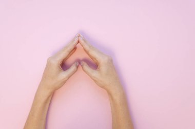 Düz aşk konsepti. Romantik sevgililer günü pembe arka planında kalp şekillendiren kadın elleri
