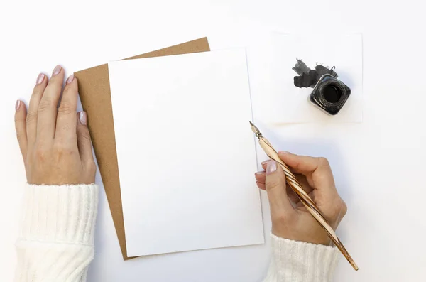 Flat lag vrouwelijke hand in witte trui schrijven bruiloft uitnodiging kaart of liefdesbrief. Handschrift concept met een inkt fles en inkt pen op een witte tafel — Stockfoto