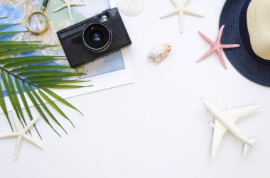 Masa üstü görünümü Seyahat blogcuları aksesuarları, beyaz arka planda yaz tatili öğeleri. Uçak, harita, kopyalama alanı olan bir kamera çerçevesi