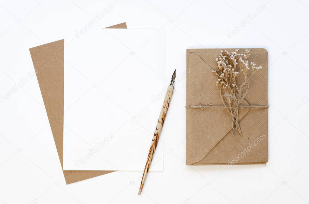Flat lay Feminine workplace with wrapped with craft paper and twine gift card and empty paper card with ink pen and dry flowers. Mockup with copy space on a white table background