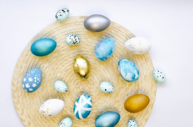 Stylish flat lay with quail and chicken, Gold leaf, white and blue easter eggs. Painted with beautiful patterns on a wicker tray