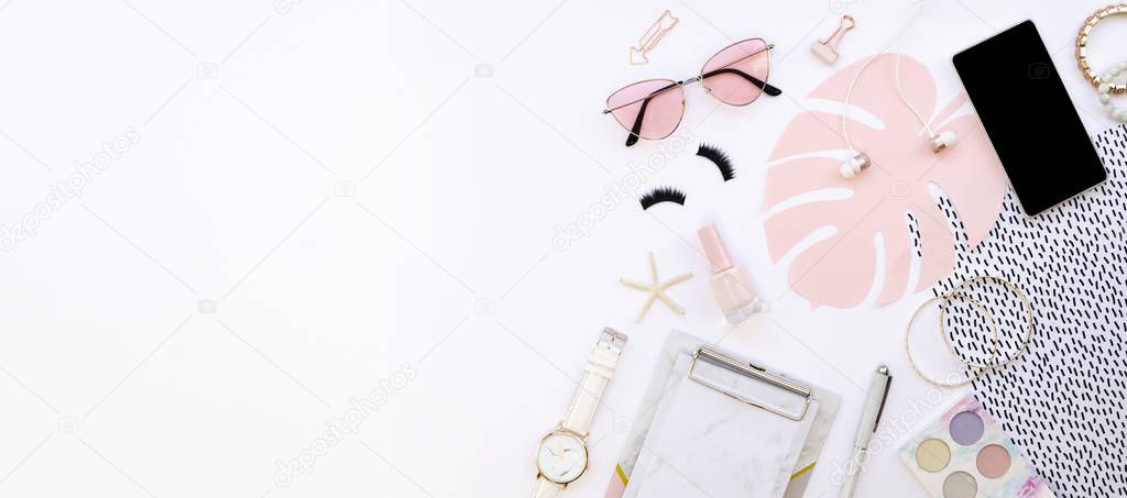 Wide banner feminine white desk with accessories and copy space. Workspace with cosmetics, glasses, mobile phone and paper craft monstera palm leaf on a white background