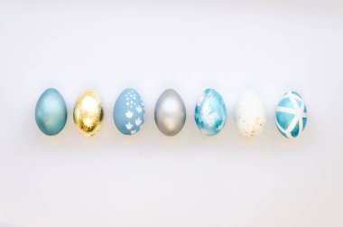 Stylish Set of 7 blue, silver and gold Easter eggs isolated on white background Ester concept. Flat lay
