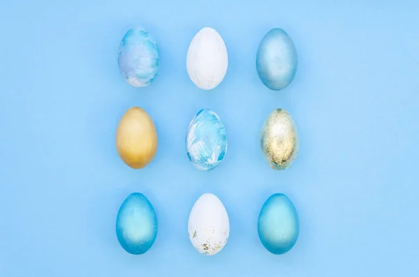 Stylish Set of blue, white and gold easter eggs isolated on light blue background. Easter concept, top view — 스톡 사진
