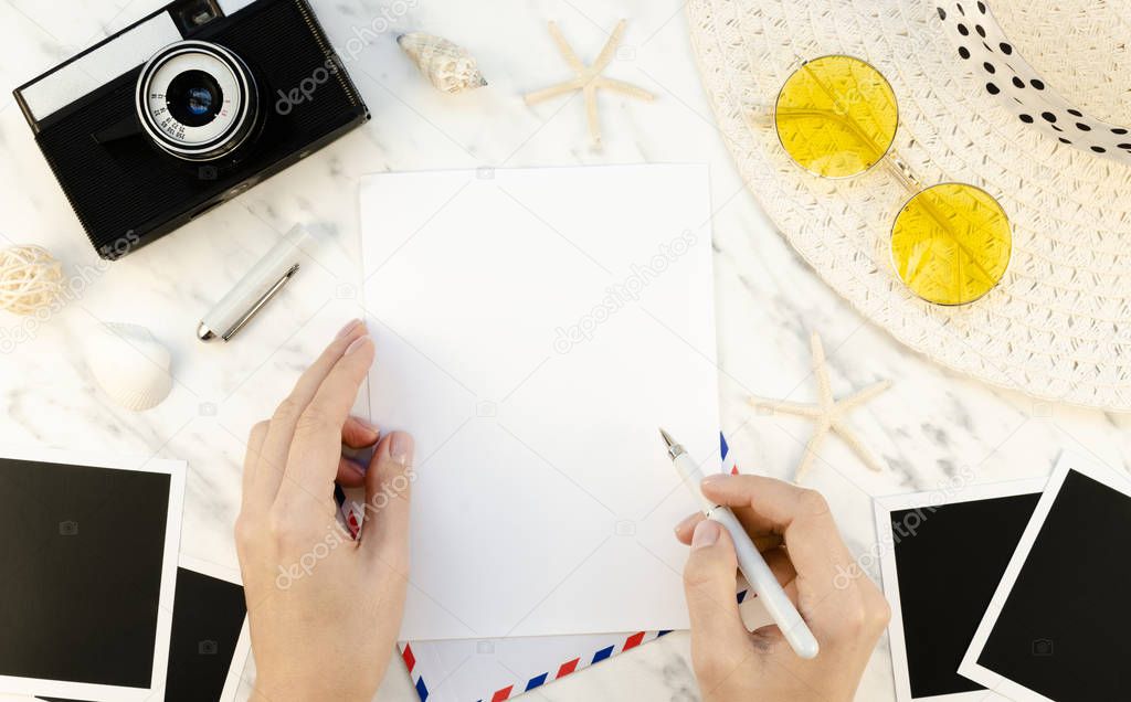 Photographer workspace desk mockup. Feminine hands writing letter airmail, bordered with vintage camera and blank old photograph