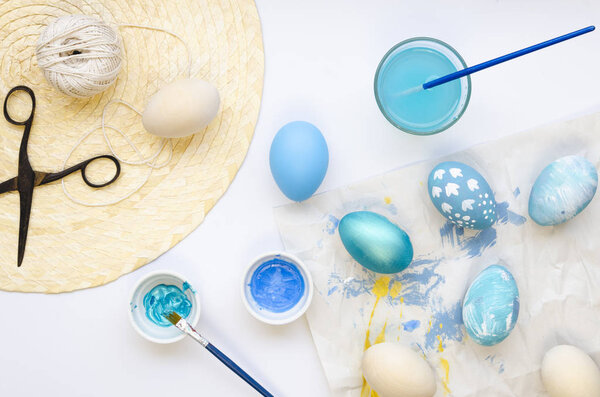 Easter eggs painting on white background. Decorating artificial wooden eggs with patterns, ribbons and twine. Top view