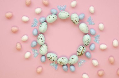 Paskalya dairesi şekil çerçevesi pembe bir masanın üzerindeki süslü bıldırcın yumurtalarından yapılmış. Harfler için boşluk olan üst görünüm