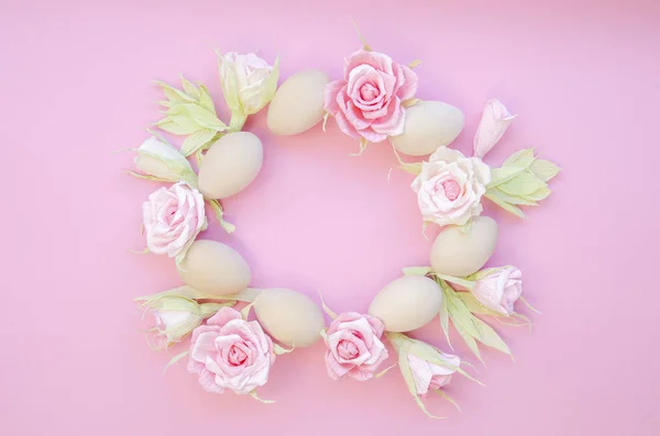 Top view Easter Frame Papercraft roses and decorative Easter eggs in circle shape on a pink background. Copy space