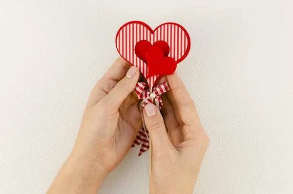 Las manos femeninas de vista superior sostienen corazones de fieltro rojo. Día de San Valentín y concepto de amor sobre fondo blanco — Foto de Stock