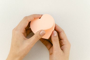 Romantik düz, kadınsı eller beyaz arka planda pembe kalp şeklinde yapışkan notlar tutuyor. 14 Şubat Sevgililer Günü tebligatı için boşluk kopyala