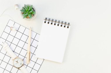 Üst görünüm beyaz masa çalışma alanı modeli. Masanın üzerinde bitki, kalem ve kadın kol saati ile boş spiral bir defter açtım. Yapılacaklar listesi konsepti yapma zamanı