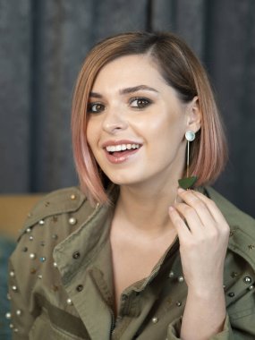 Beautiful girl vertical portrait in military clothes demonstrates her professional makeup. Looks in camera and smiling