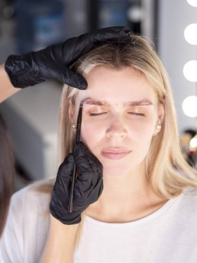 Kaş şeklini düzelten modelin dikey portresi. Fırçayla çalışan bir güzellik uzmanı