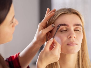 Mikro patinaj işleminden sonra kaşlarını tımar eden makyöz.