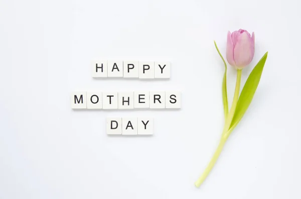 Texto Feliz Día de las Madres hecho de cubos de madera con flor de tulipán aislado en blanco. Puesta plana — Foto de Stock