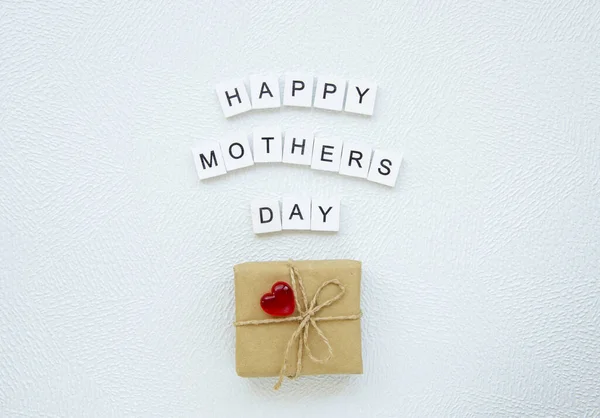 Día de las madres caja de regalo con corazón y letras de madera hecho signo Feliz día de las madres sobre fondo blanco. Vista superior — Foto de Stock