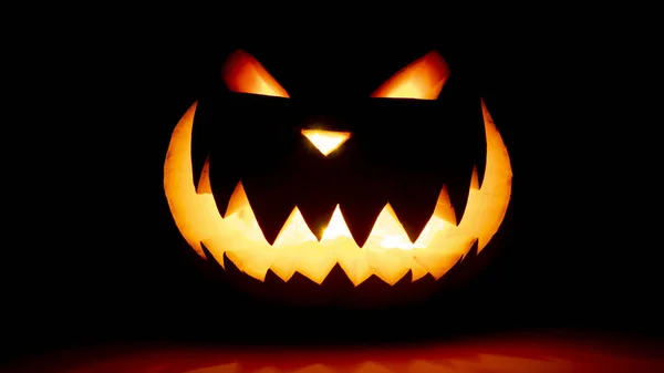 Skrämmande ansikte halloween pumpa på en svart bakgrund. Lysande leende glödande ansikte — Stockfoto