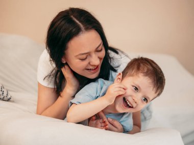 Anne ve 4 yaşındaki çocuğu bir kanepede uzanıp gülüyorlar. Anneler Günü konsepti