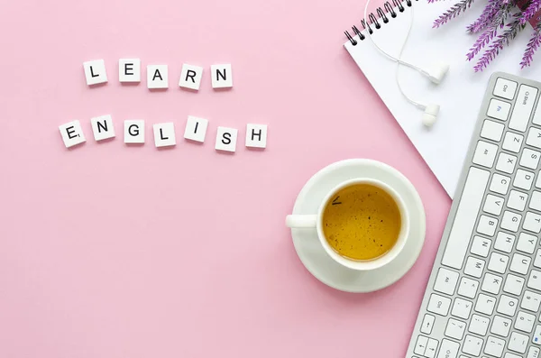 Feminino rosa desktop flat lay com sinal SAIBA INGLÊS escrito com letras cubo de madeira, teclado, fones de ouvido e xícara de chá — Fotografia de Stock