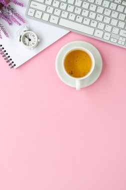 Pembe kadın masasında klavye, çalar saat ve bir fincan çay. Kopyalama alanı olan dikey asgari düzlem