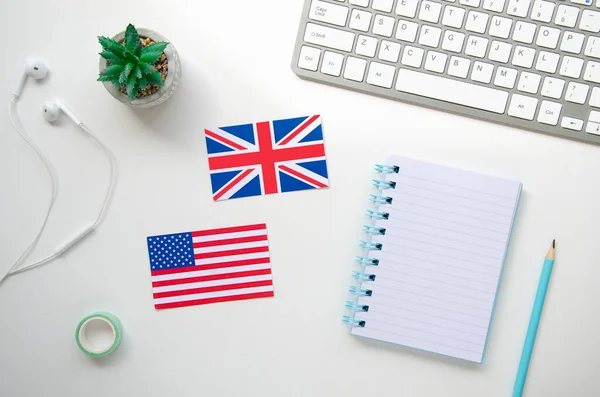 Флаги Великобритании и США на белом столе школы с клавиатурой и наушниками. Изучение иностранного языка в домашних условиях — стоковое фото