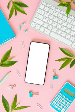 Dişil pembe minimal masaüstü. Klavye, durağan ve pembe arka plandaki yapraklarla çerçevelenmiş boş akıllı telefon ekran modeli. Üst görünüm, düz görünüm, dikey
