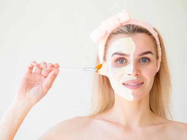 Perawatan kecantikan. Portrait of spa caucasian girl menerapkan masker wajah di setengah wajah dengan Silicone Face Mask Brush — Stok Foto
