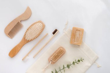 Banyo için sıfır atık seti plastiksiz doğal ahşap aksesuarlar ve beyaz arka planda okaliptüs dallarıyla yatıyordu.