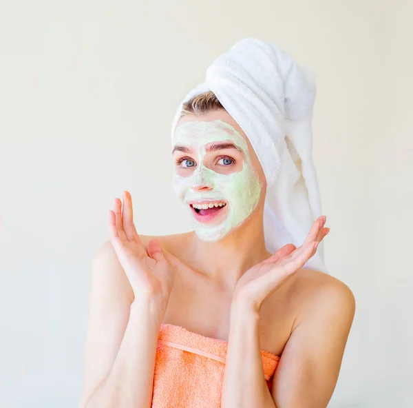 Terkejut tersenyum wanita dengan masker SPA wajah dan handuk di kepalanya. Potret close-up dipotong. Prosedur spa buatan sendiri — Stok Foto