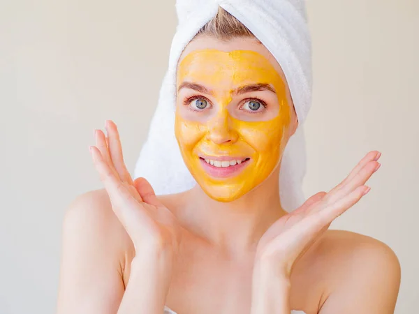 Keindahan wajah dan prosedur SPA. Portrait of young Woman with Towel on her head applicated Natural Facial Gold Mask at Home — Stok Foto