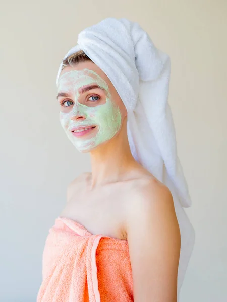 Homemade face treatments. Side portrait of a smiling woman with a towel on her head looking on camera — Stock Photo, Image