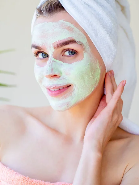 Homemade spa mask for face. Beautiful woman with green natural facial clay mask. Beauty treatments. Close Up portrait. Touching her face