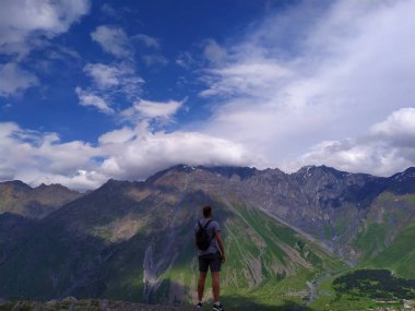 Erkek gezgin dağlara bakar.