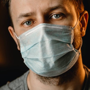 Koruyucu maskeli bir adam kameraya bakar. Virüs koruması, kendini izole etme..