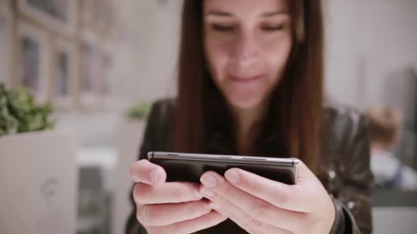 Primer plano de las manos de la mujer usando un teléfono inteligente. Linda chica morena sonriendo . — Vídeo de stock