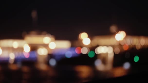 Hermosa vista nocturna de la ciudad. Luces borrosas de la ciudad reflejándose en el agua . — Vídeo de stock