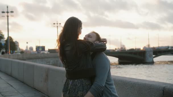 A couple in love swirling around, smiling, kissing at the sunset. Bridge, river at the background, slow mo — Stock Video