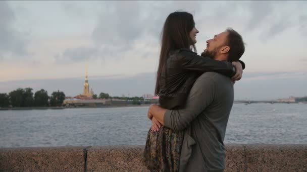 Красивая влюбленная пара, кружащаяся вокруг, улыбающаяся, целующаяся Петропавловская крепость, река на заднем плане, медленное время — стоковое видео