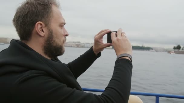 Vue de côté d'un bel homme prenant des photos tout en visitant Saint-Pétersbourg, en Russie. Homme utilisant son smartphone, slow mo — Video