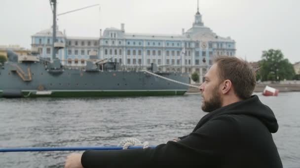 Turismo en San Petersburgo. Hombre guapo explora, toma fotos del crucero Aurora, utiliza su teléfono inteligente, lento mo — Vídeos de Stock